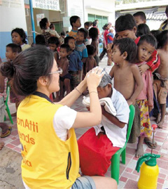 ‘라온아띠’3기로 캄보디아에 간 대학생 자원봉사자가 아이들의 머리를 감기고 있다. /KB국민은행 제공