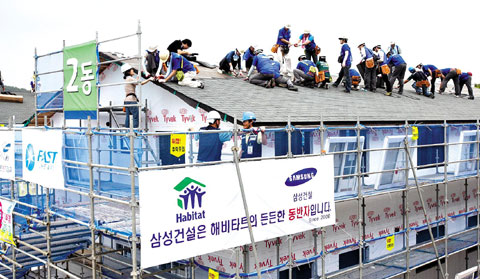  삼성물산 임직원들이 3층 높이의 지붕 위에서 집짓기에 땀을 흘리고 있다. 해비타트운동으로 지어지는 집의 공정 중 60%이상이 이런 자원봉사자들의 힘으로 이루어진다. /삼성물산 제공