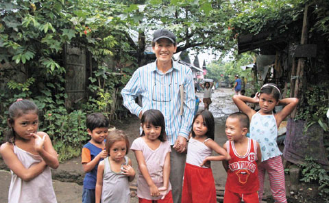 이종식 기아봉사단원이 영양급식 지원을 받는 아이들과 함께 웃고 있다.