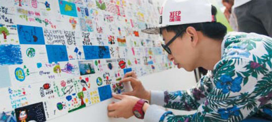 지난 10일 개최된‘아트업 페스티벌’에 참여한 팝아티스트 찰스장이 2000명의 시민과 함께한 공공아트‘해피 투 게더(Happy together)’에 폐카드로 만든 그림을 붙이고 있다. /위누 제공