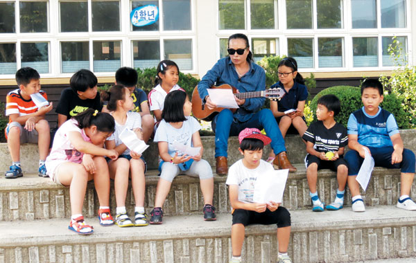 김태원이 강원도의 한 초등학교 아이들과 함께 기타를 연주하고 있다. 폴제페토의 수익금은 강원도 아이들이 음악을 접할 기회를 만드는 데 쓰인다. / 폴제페토 제공 