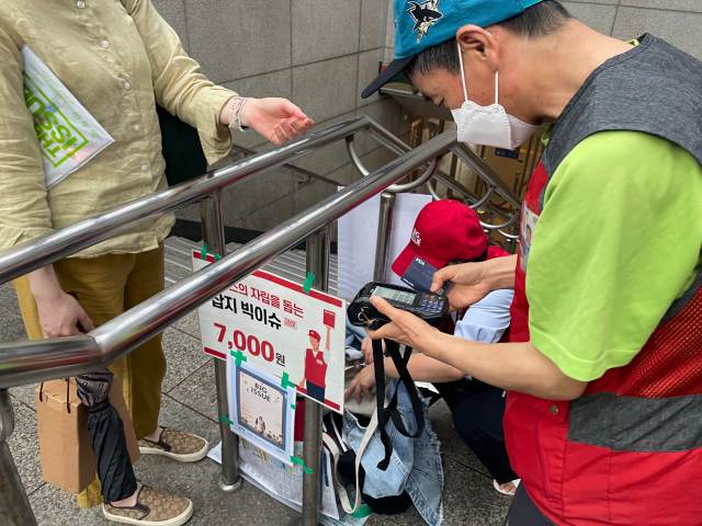 오현석 빅이슈 판매원이 지난달 23일 서울지하철 고속터미널역 8번 출구 앞에서 첫 손님을 만나 카드 단말기로 결제하고 있다.