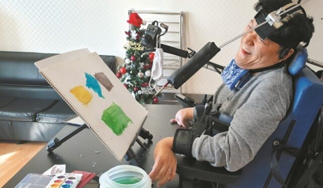 뇌병변과 지적장애를 가진 중복장애인 이용수씨가 헤드포인터에 붓을 연결해 그림을 그리고 있다. 